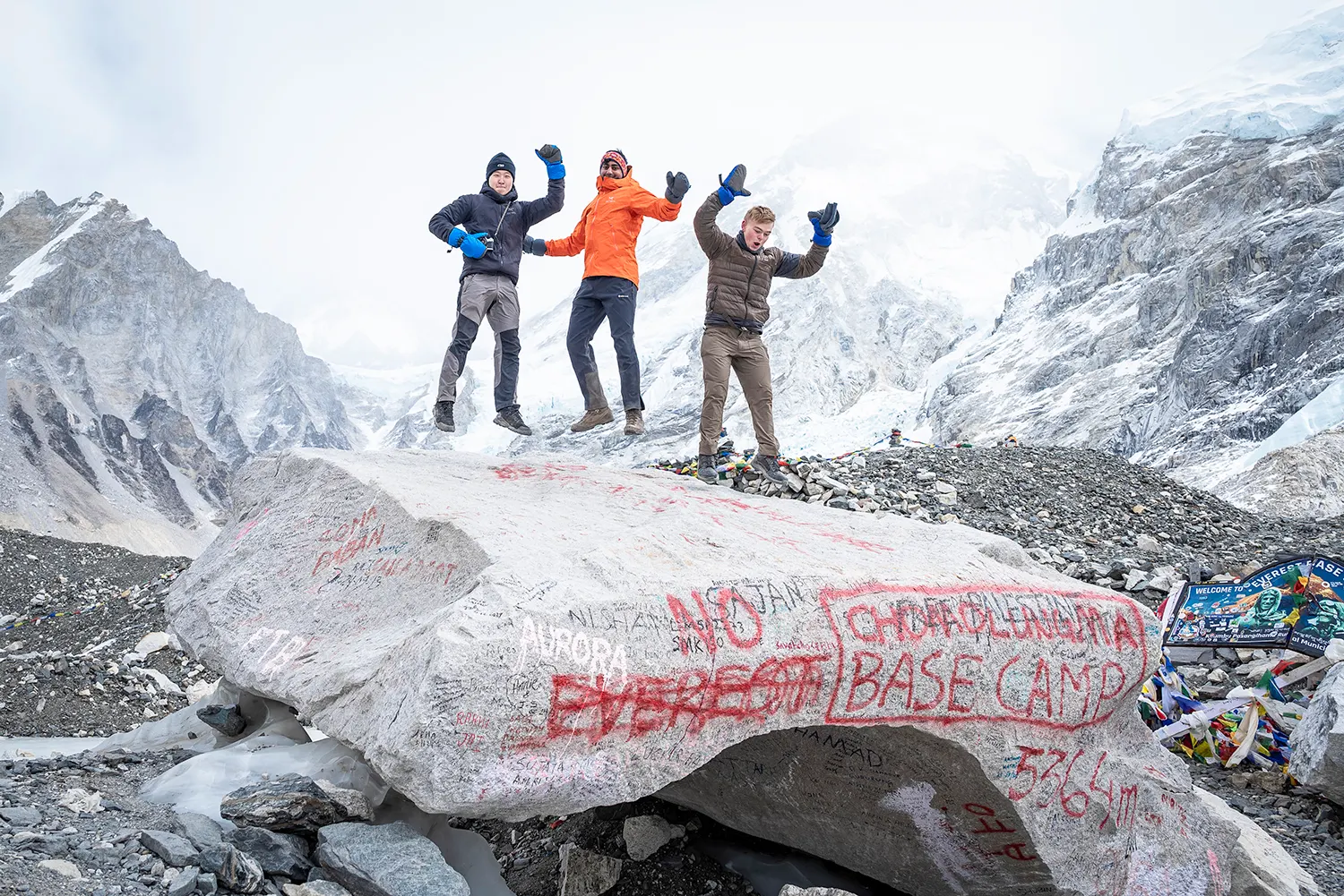 Trekker jumping at Everest Base Camp with snowy Himalayan peaks behind.